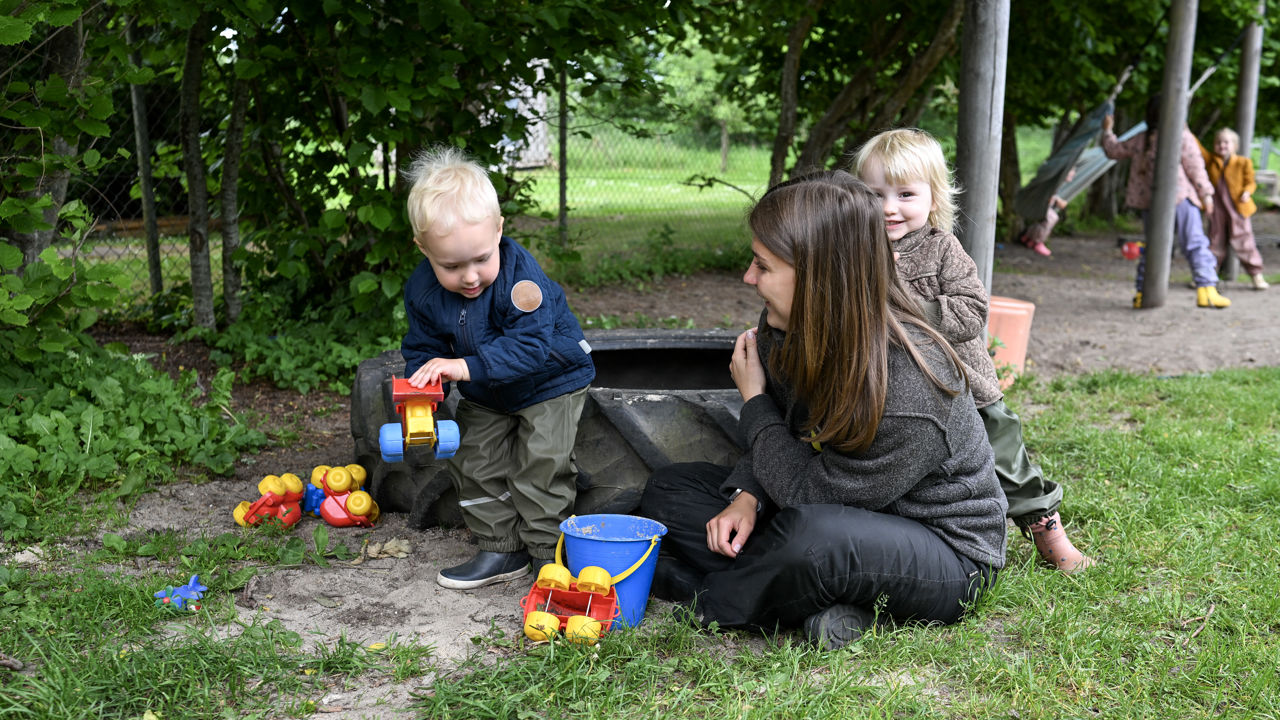 Børn og voksen leger med jord