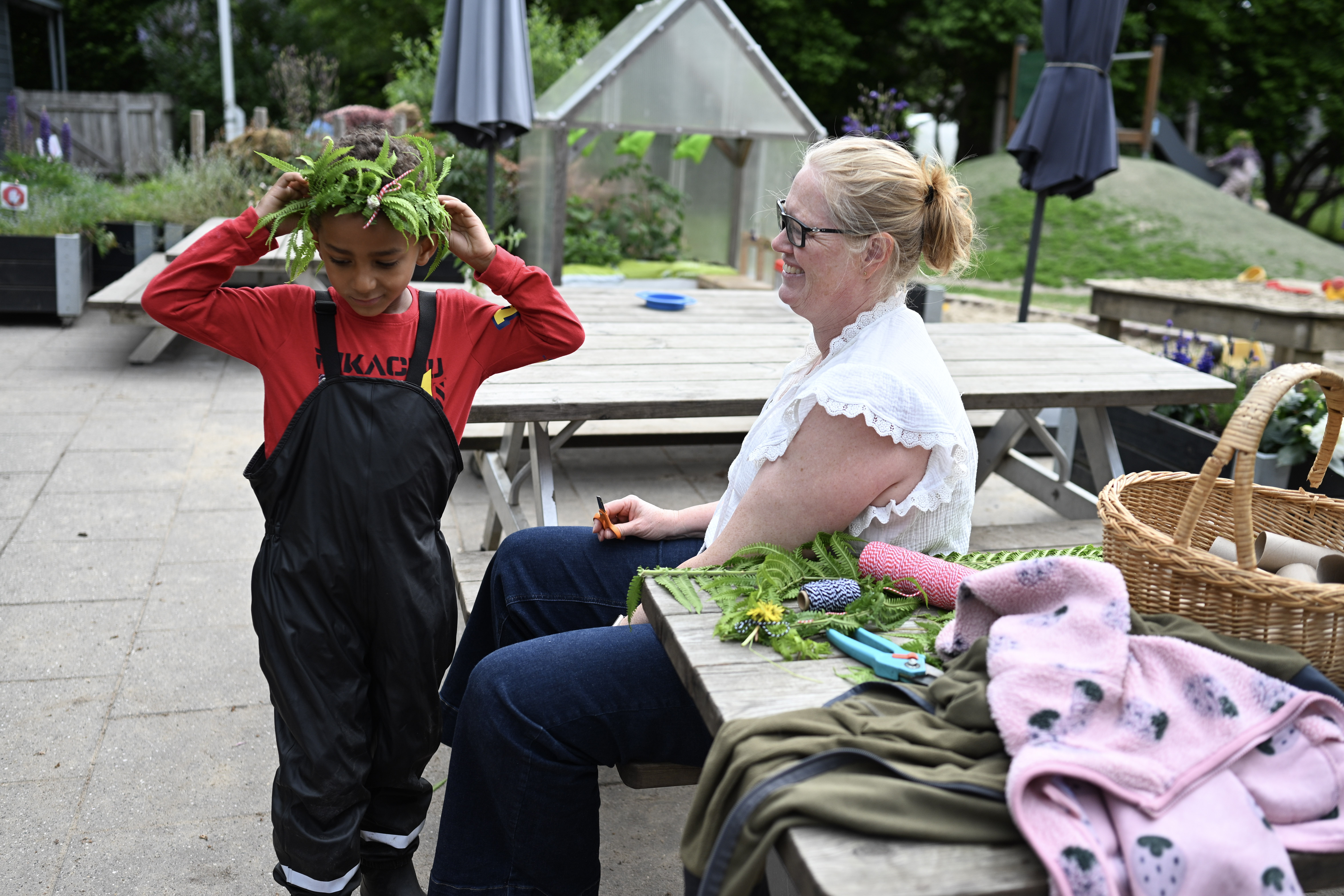 Voksen giver barn plantekrans på hovedet
