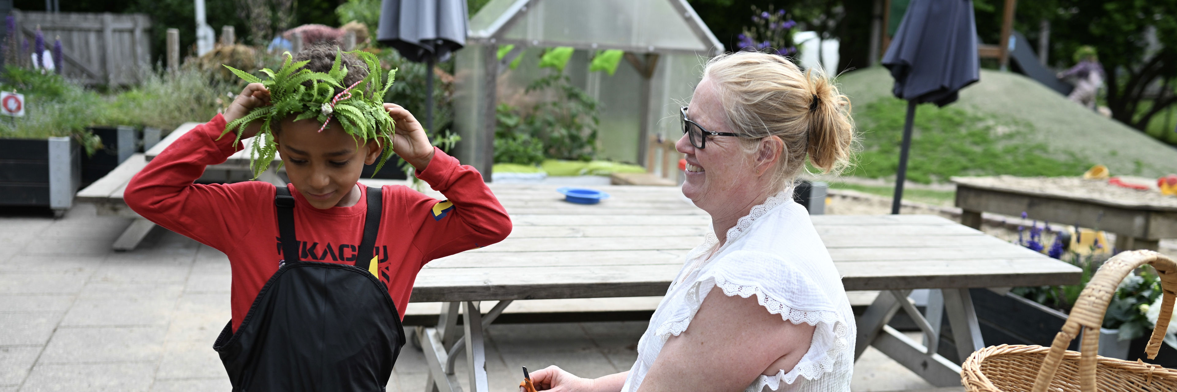 Voksen giver barn plantekrans på hovedet